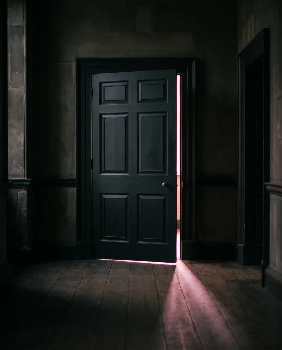 Porta socchiusa con luce calda, invito a entrare